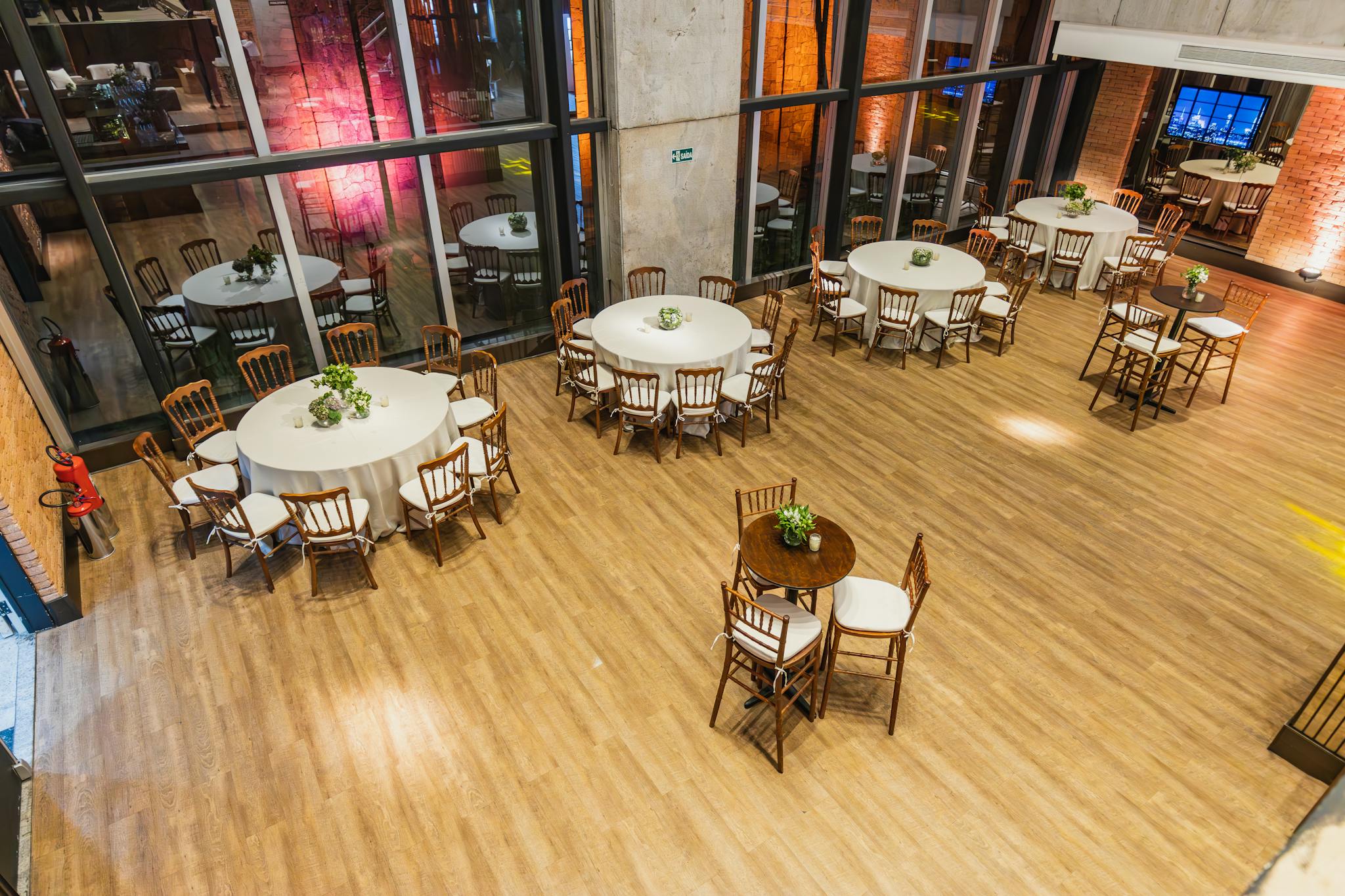 Spacious indoor event hall with round tables and chairs elegantly arranged for a special occasion.